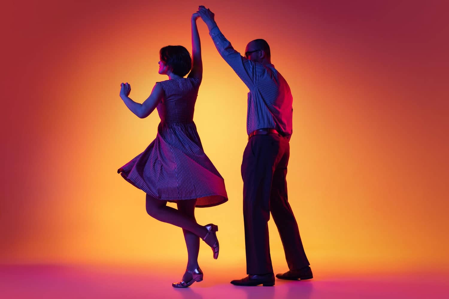kompr portrait of artistic couple dancing retro style dance isolated over gradient orange yellow background in neon light